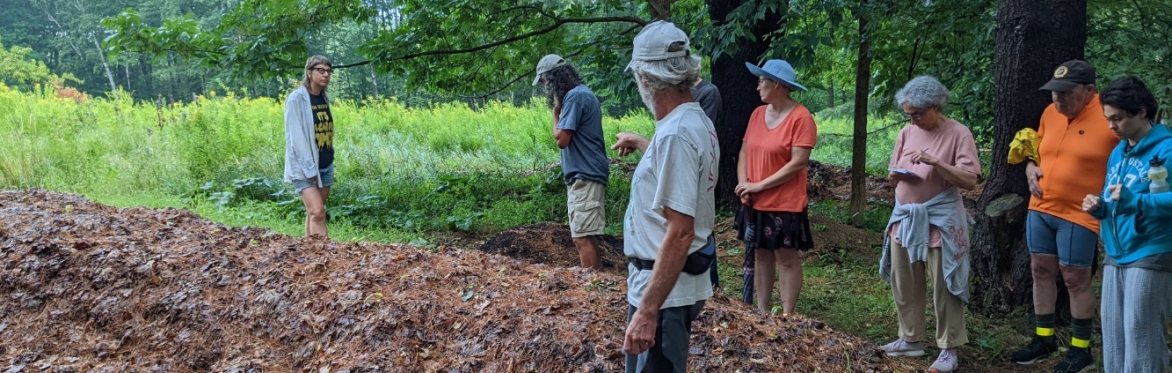 Tom Vigue leads a group of people on a tour of his leaf compost piles