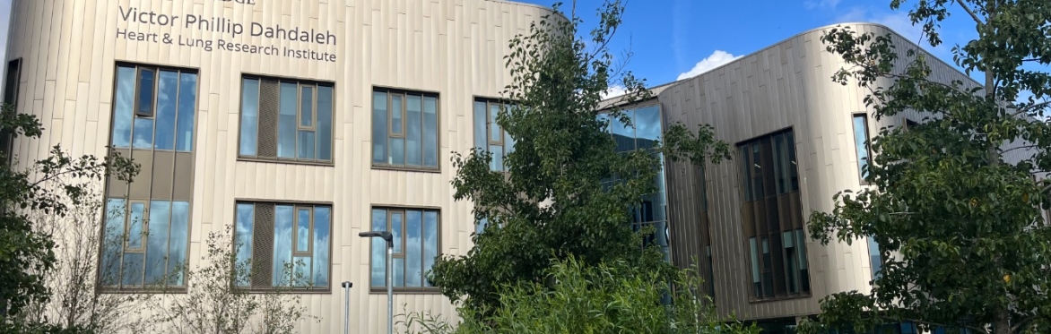 An external image of a bronze building with trees in the foreground.