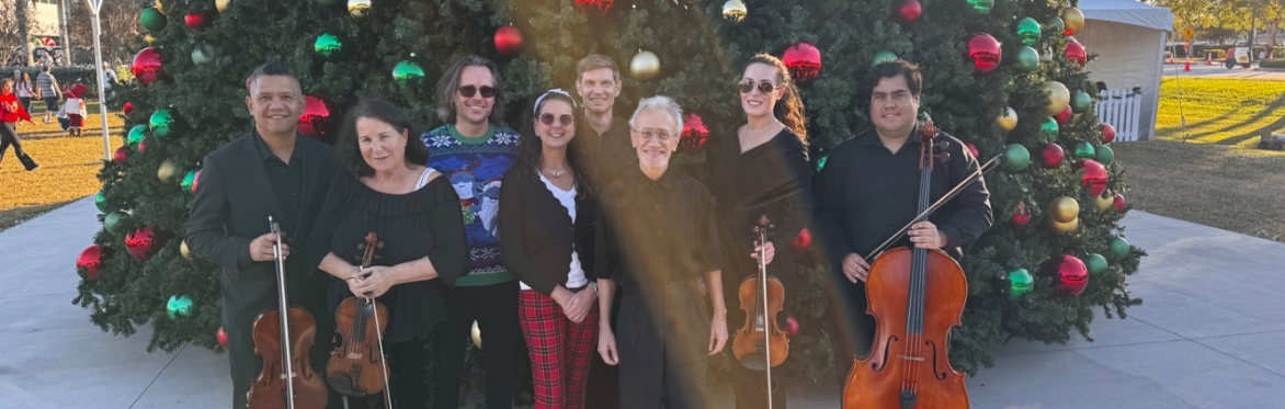 Musicians standing in front of a Christmas tree.