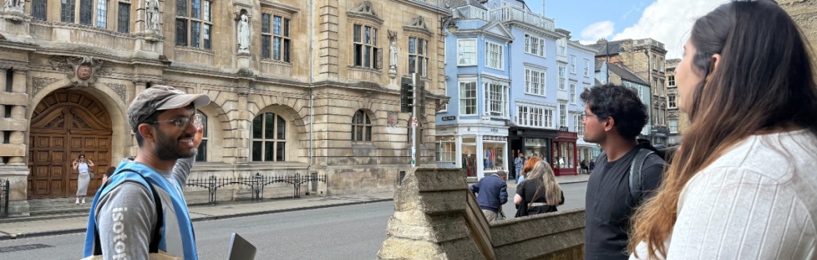 Woman standing with a tote bag next to a group of walking tour attendees next to Baliol College