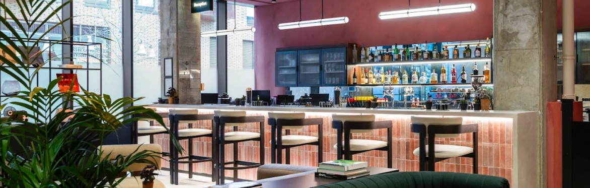 Modern bar and lounge interior at Qube, London, featuring plants and seating.