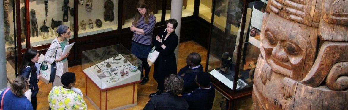 Group of people inside an anthropology museum, with totem pole on the right hand side