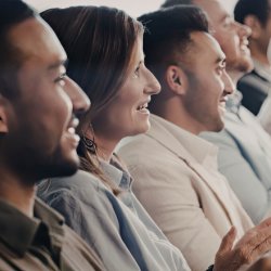 A group of people sitting in a row, smiling and applauding.