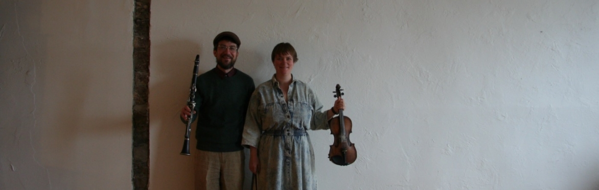1 man holding a clarinet, 1 woman holding a fiddle
