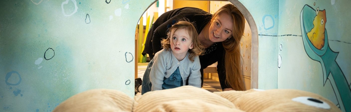 A woman and small child explore a play structure together
