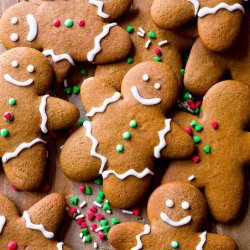 Ginger bread men biscuits decorated with white icing faces and red and green sprinkles