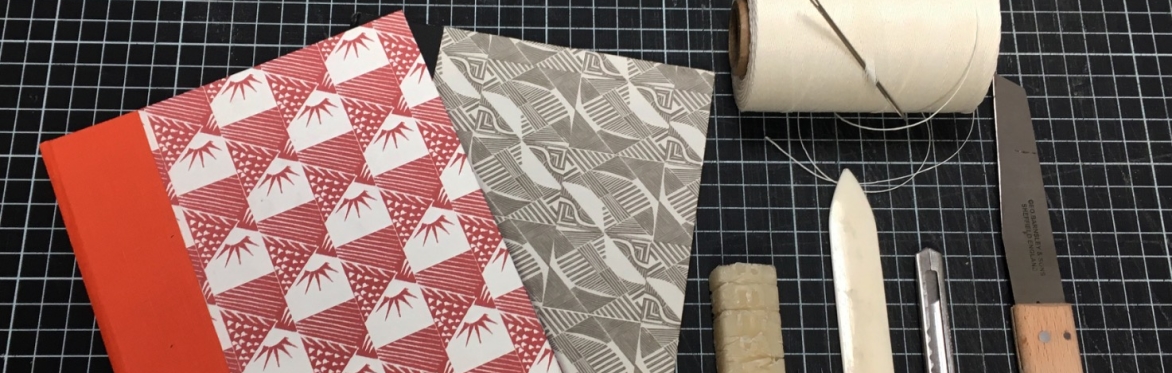 An array of bookbinding tools along with a handover book with red printed pattern