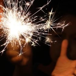 A close up image of an adult holding a lit sparkler