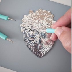 image shows an embossed metal heart design with hand tools