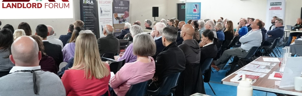 Attendees at the landlord forum sat in rows, watching a presentation from one of the speakers who is stood at the front, holding a microphone