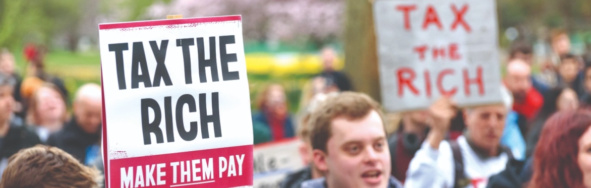 placards on protest read 'Tax The Rich: Make them Pay'