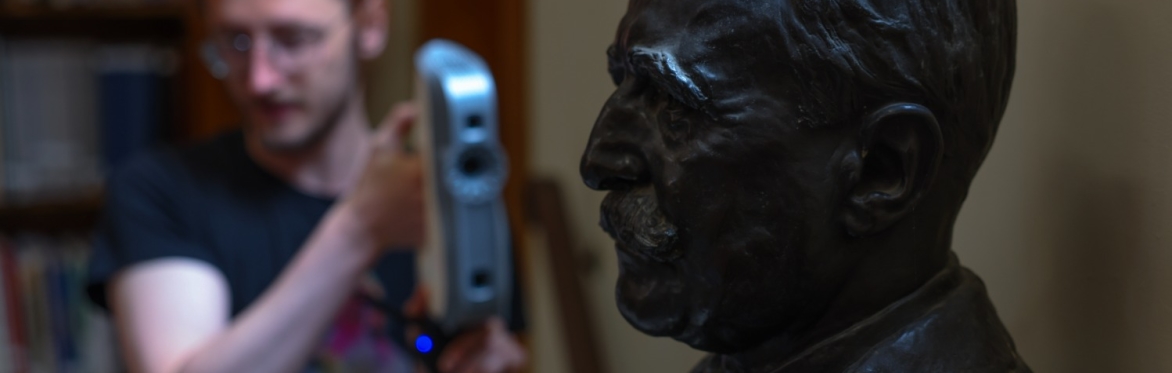 A photo of someone pointing imaging equipment at a dark bust sculpture.