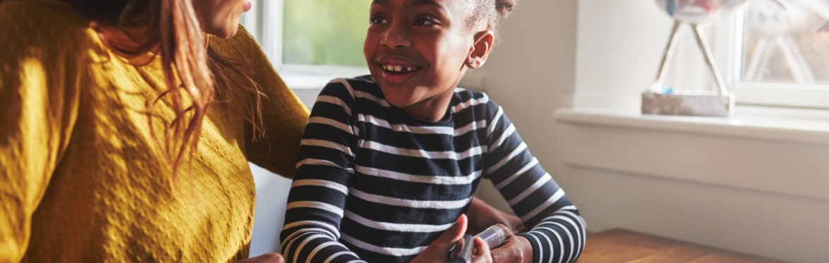 Mum and daughter smile at each other while working on spelling homework
