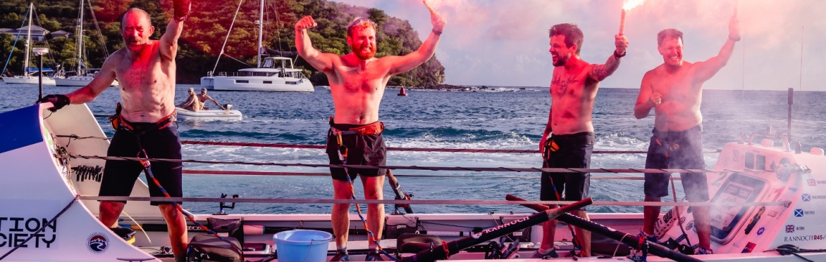 The 4 rowers from Team Give Us A Wave hold Flares above their heads after completing the 3,000 mile row across the Atlantic Ocean