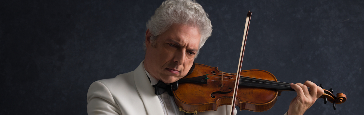 A man in a white suit with white hair plays a violin.