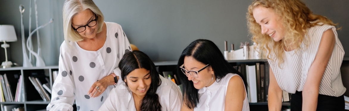 Four women in an office looking over papers together.