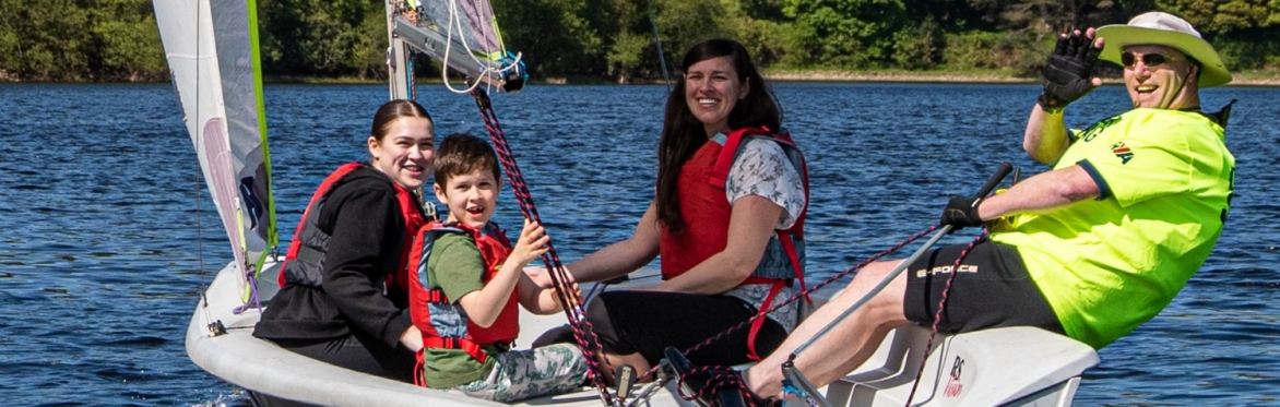 A happy crew trying dinghy sailing in a beautiful lake