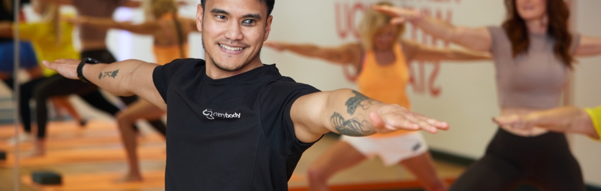 Group of people, with a man in an Everybody shirt at the front, taking part in a yoga session