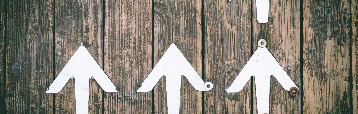 White arrows pointing upwards against a wooden background