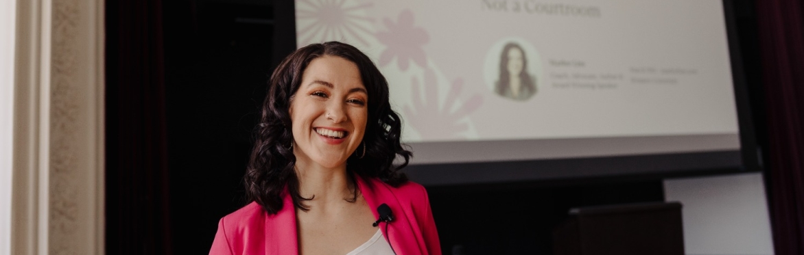 Woman smiling in front of screen saying "Restorative Justice for Sexual Harm"