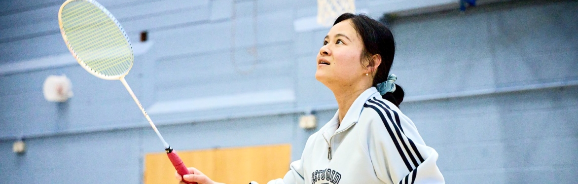 Person playing badminton in a sports hall
