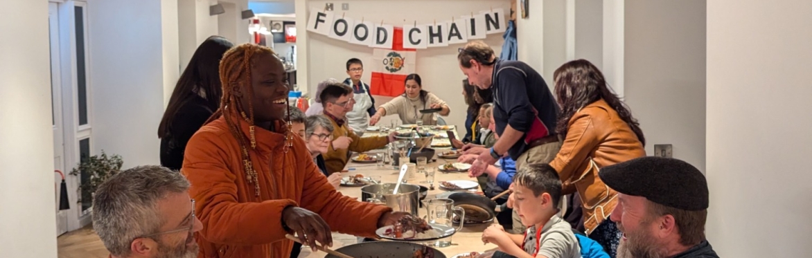 A photo showing a group of people eating together around a long table