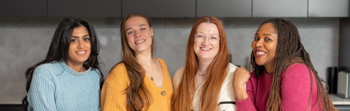 an image of the four female dietitians at Mental Health Dietitians, wearing bright colours, stood in a kitchen, similing at the camera.