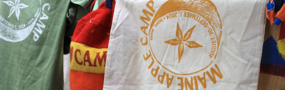 A screenprinted bandana, which reads "Maine Apple Camp" dries on a clothes line.