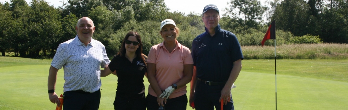 A golf team smiling out on the golf course.