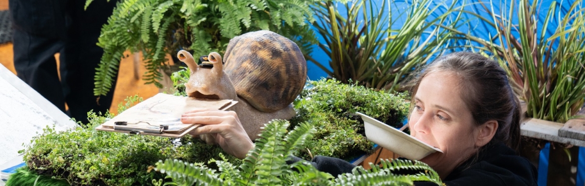 An artist with a sculpture of a snail.