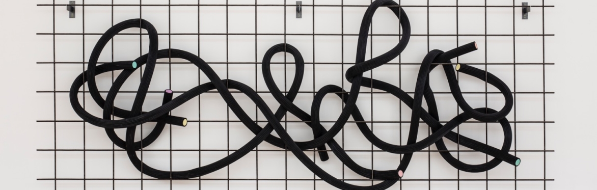 A sculpture that looks like black laces that is fed through a metal grid