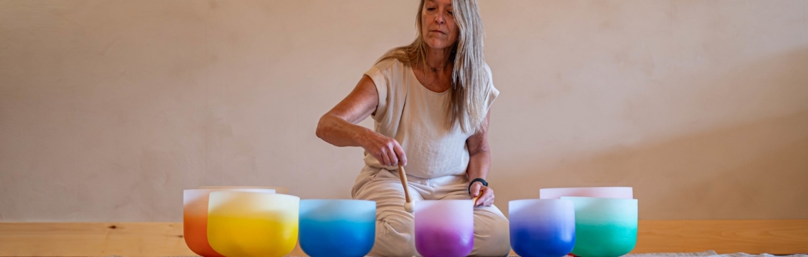 Kimberlee Grogan plays one of a variety of crystal sound bowls in front of her.