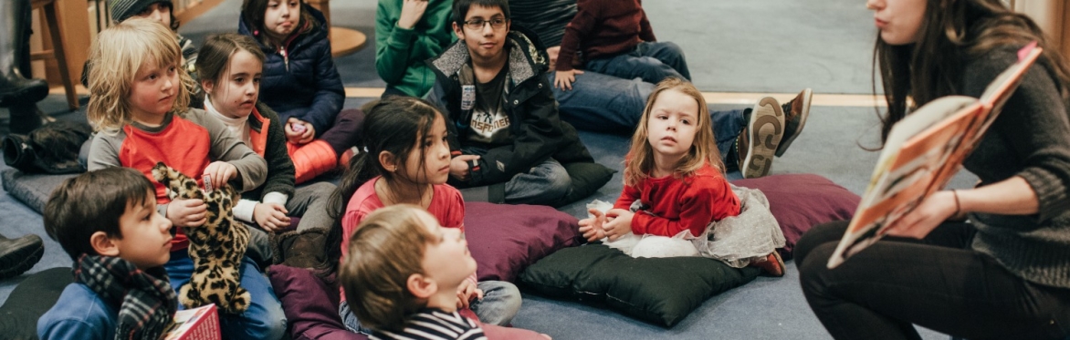 Librarian reading a story to a group of childen.