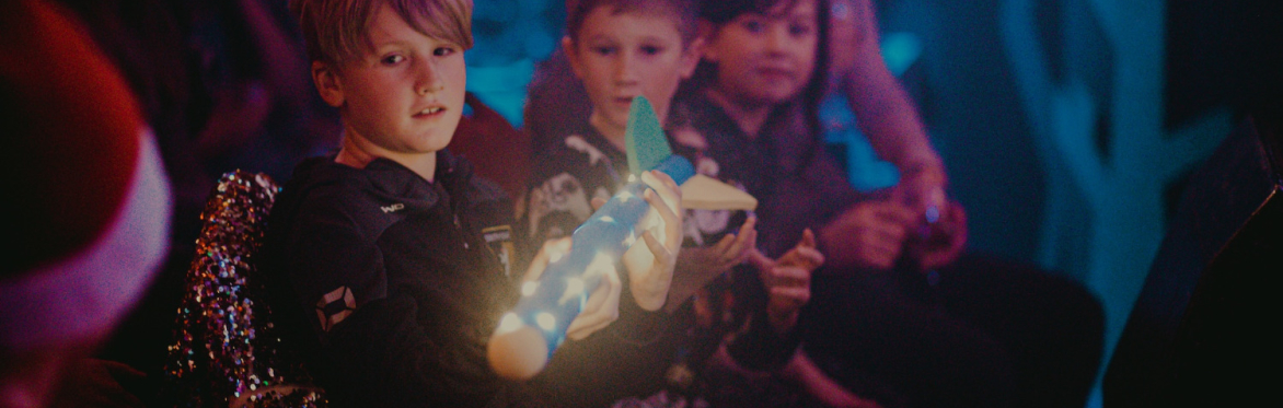 Children in the audience for pantomime passing a light-up prop along