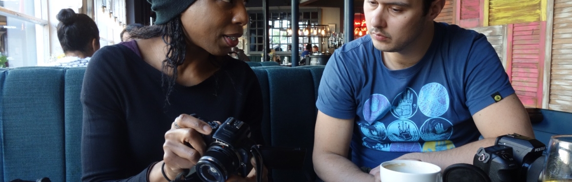 Photography tuition class teacher and student sat at table with cameras