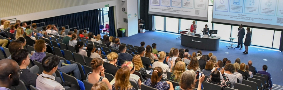 Conference attendees sitting in an auditorium facing speakers
