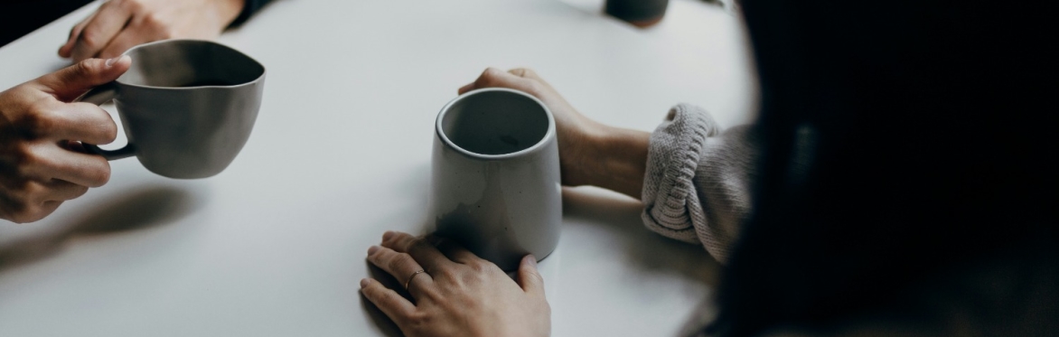 Two people talking holding coffee