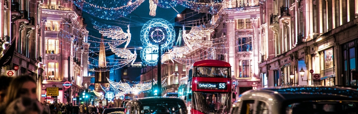 a photo looking north on Regent's Street in London up through Oxford Circus at night.  Taxis in the foreground, a red 55 bus in the mid ground and christmas lights cover the skies