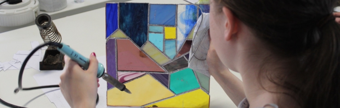 Woman holding her stained glass panel upto the light
