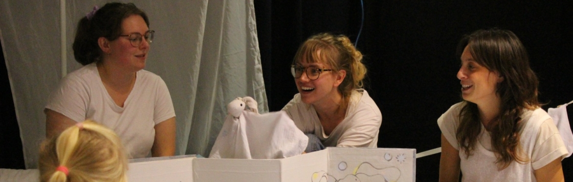 3 performers with a puppet popping up behind a screen being watch by a child