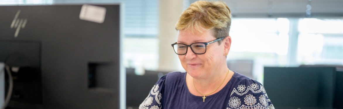 Middle aged woman sits at her computer working at the desk.