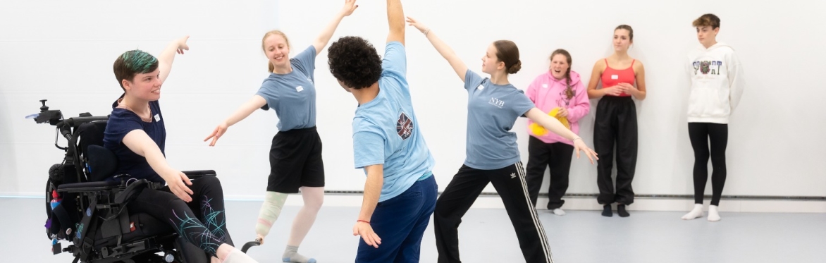 Image features NYB All In! participants dancing Ballet in a light studios with floor length windows.