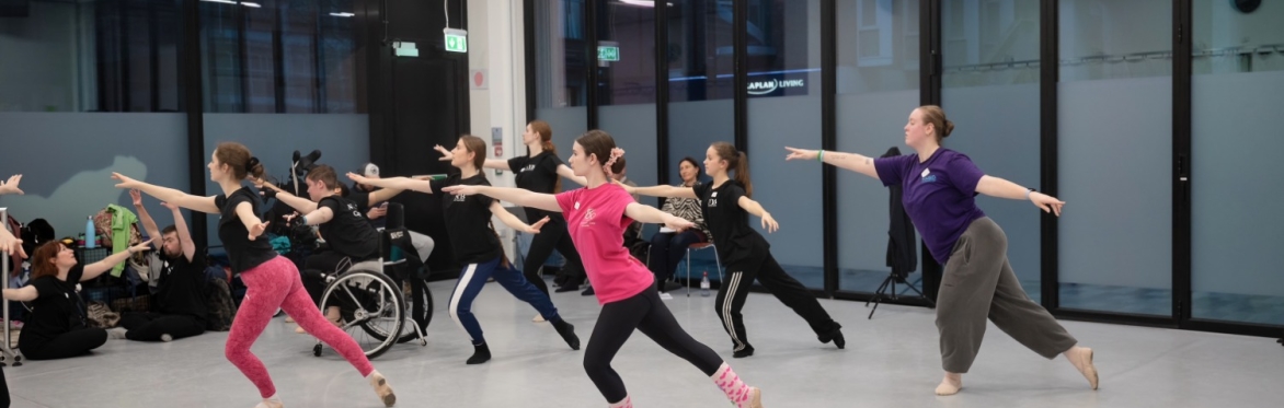 Image features NYB All In! participants dancing Ballet in a light studios with floor length windows.