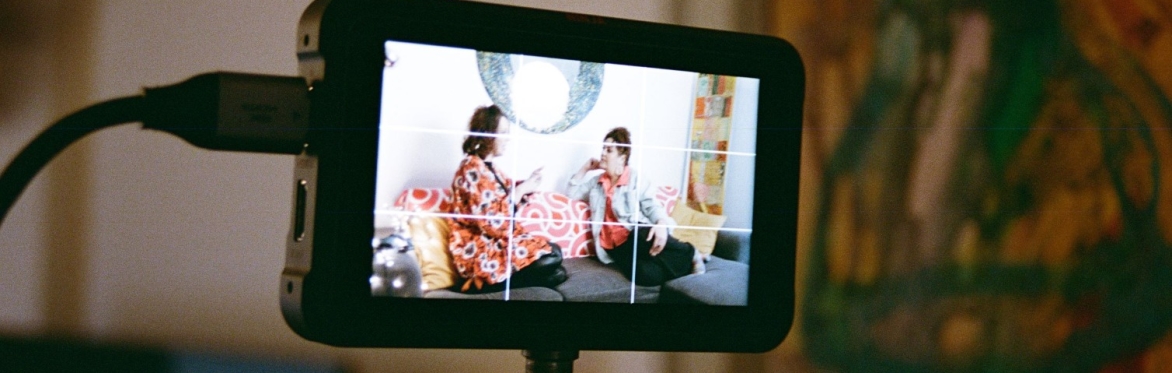 A digital camera viewfunder shows two people seated talking