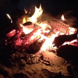 a hot campfire burning with logs glowing red and orange
