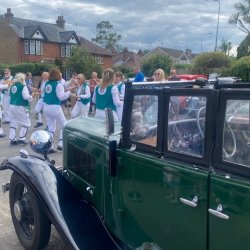 Morris dancers in green jackets and white strides with Morris classic Car