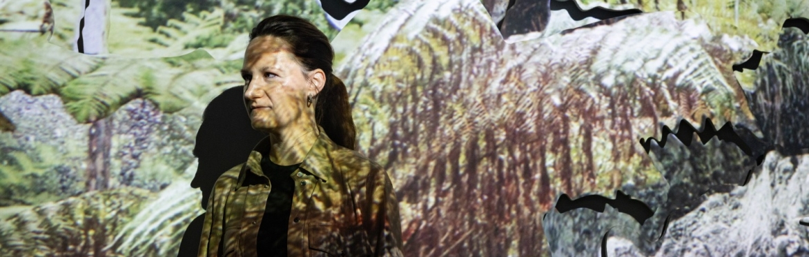 Artist Noémie Goudal with a video projection of plant photography projected on her and on the background