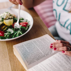 woman reading at a table while eating