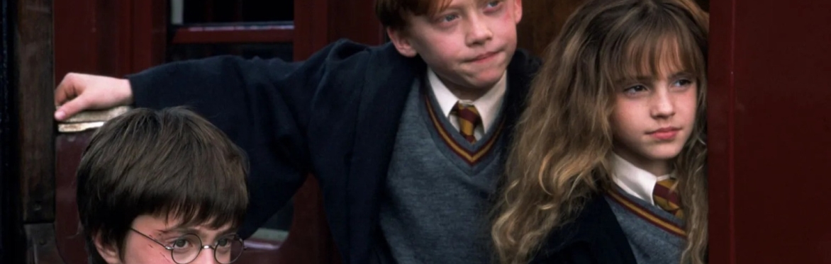 A young boy named Harry Potter with black hair and black round glasses is holding a snitch (gold with wings). Film title described as Harry Potter and the Philosopher's Stone.