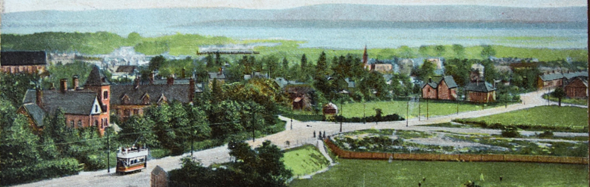 A coloured drawing of Poole Harbour from Constitution Hill. In the foreground is fields, houses, and a tram that runs across the land. In the background lies the harbour.